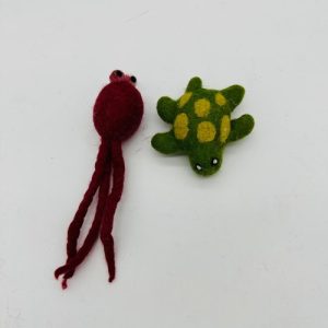 A handmade felt turtle pet toy with a green body and yellow shell spots, featuring small white eyes.